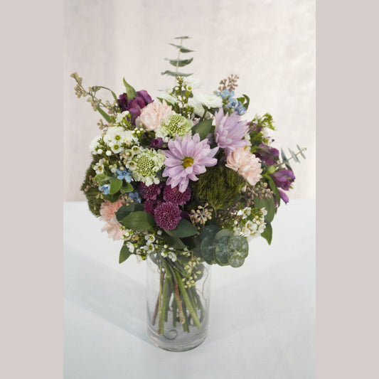 Purple spray mums, eucalyptus, and fresh, local flower arrangement in a glass vase