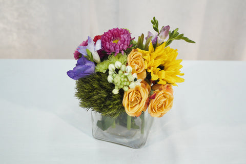 small flower arrangement in a cube glass vase