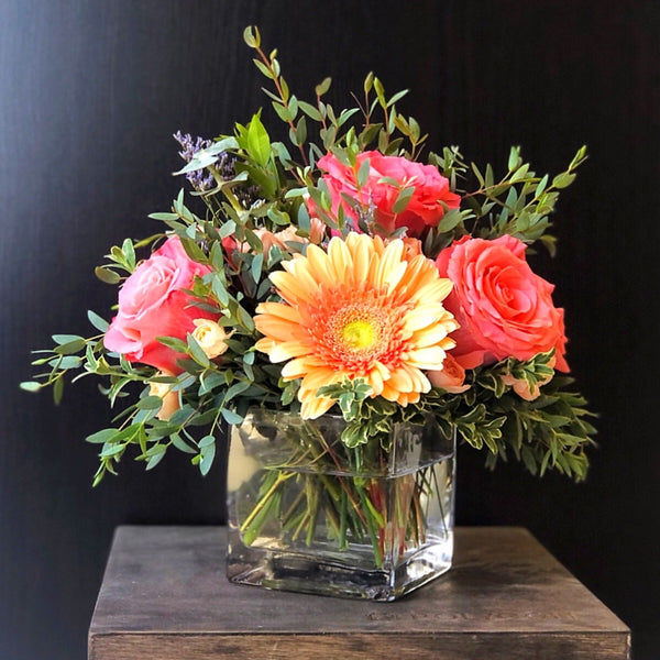 peach gerber daises and pink roses in a glass vase